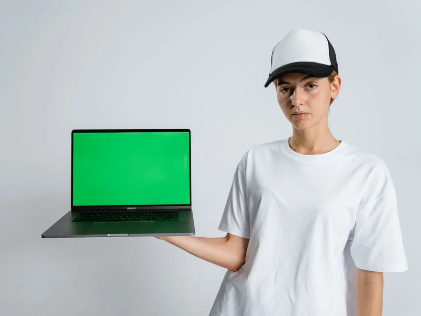 A smartphone placed in a miniature cart on a laptop represents online shopping and digital payment.